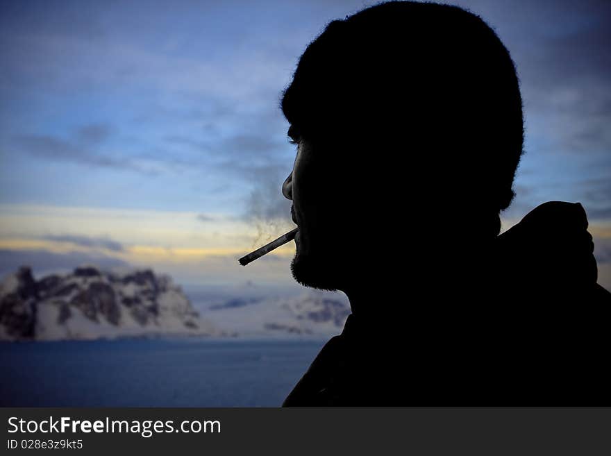 Silhouette of male smokers in the background of the mountains of Antarctica