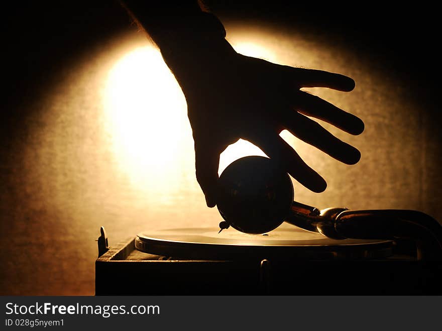 Gramophone silhouette with the hand putting the needle on the disc. Gramophone silhouette with the hand putting the needle on the disc