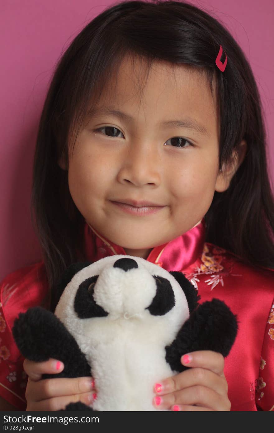 Little asian chinese girl holding a panda bear with a red silk dress on. Little asian chinese girl holding a panda bear with a red silk dress on