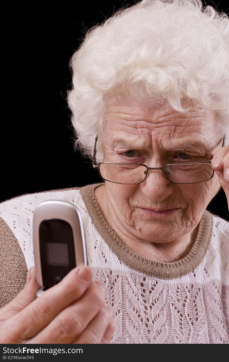 Old woman and the mobile phone isolated in black background