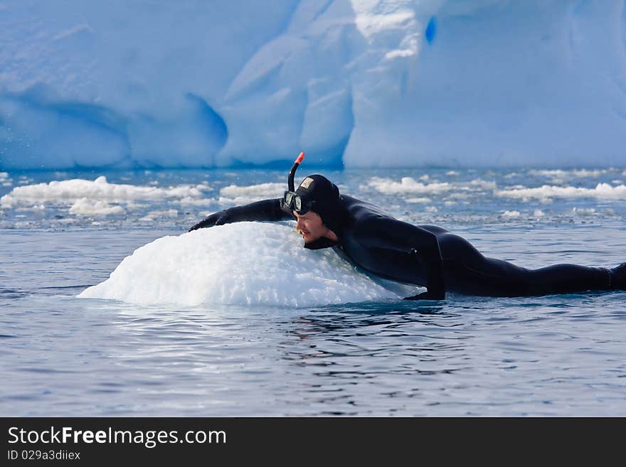 Diver on the ice against the blue iceberg. Antarctica