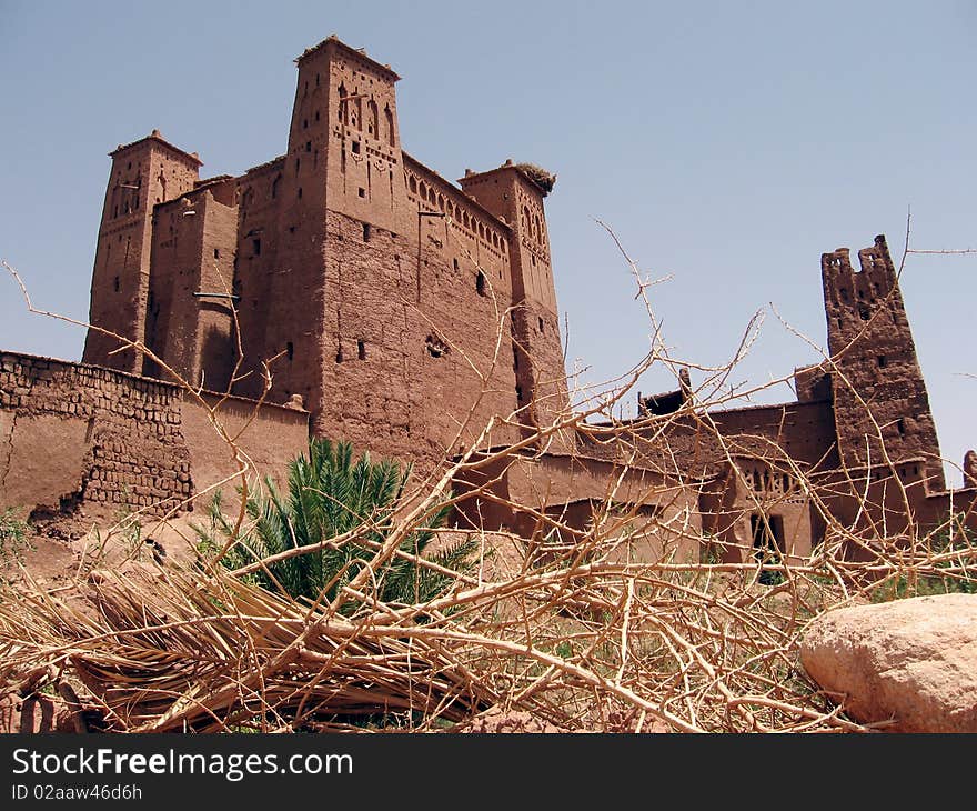 Moroc-The Kasbah of Aït Benhaddou, is a 'fortified city', or ksar, along the former caravan route between the Sahara and Marrakech in present-day Morocco. is a term describing a Berber village consisting of generally attached houses, often having collective granaries and other structures (mosque, bath, oven, shops) widespread among the oasis populations of the Maghreb (northern Africa.) Ksars are sometimes situated in mountain locations to make defense easier; they often are entirely within a single, continuous wall. The building material of the entire structure is normally adobe, or cut stone and adobe. The idea of the ksar as a granary is a confused notion of two things, the granary itself, found within a ksar, and the ksar, which is a village, normally with granaries within it. Ksars form one the main manifestations of Berber architecture.