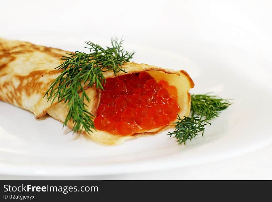 Pancake with red caviar on a white plate