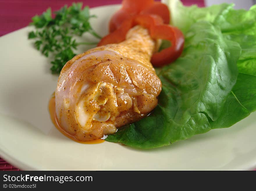 Chicken leg on plate with spices.