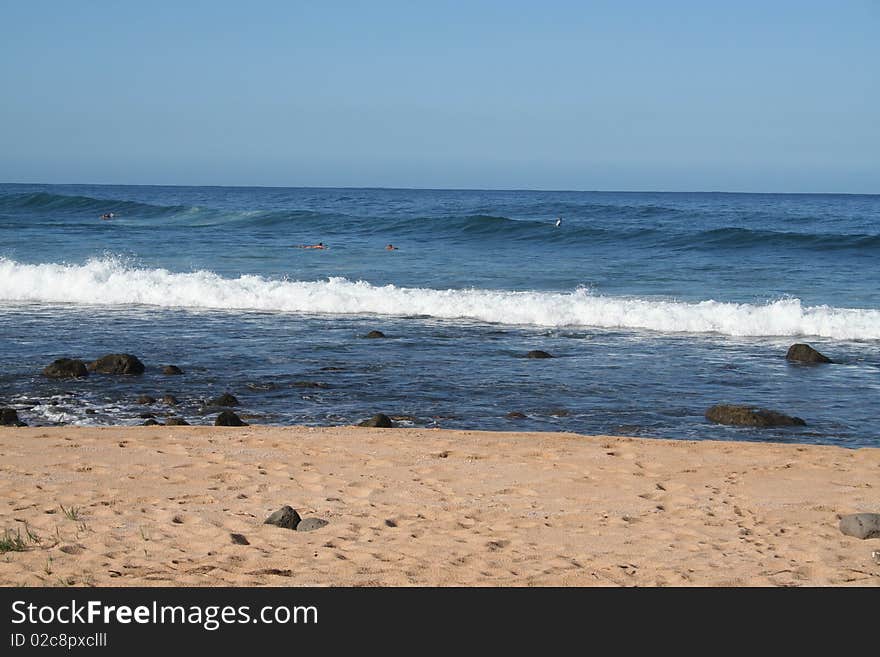 People on surfboards await waves in the water at a Molokai, Hawaii beach. People on surfboards await waves in the water at a Molokai, Hawaii beach.