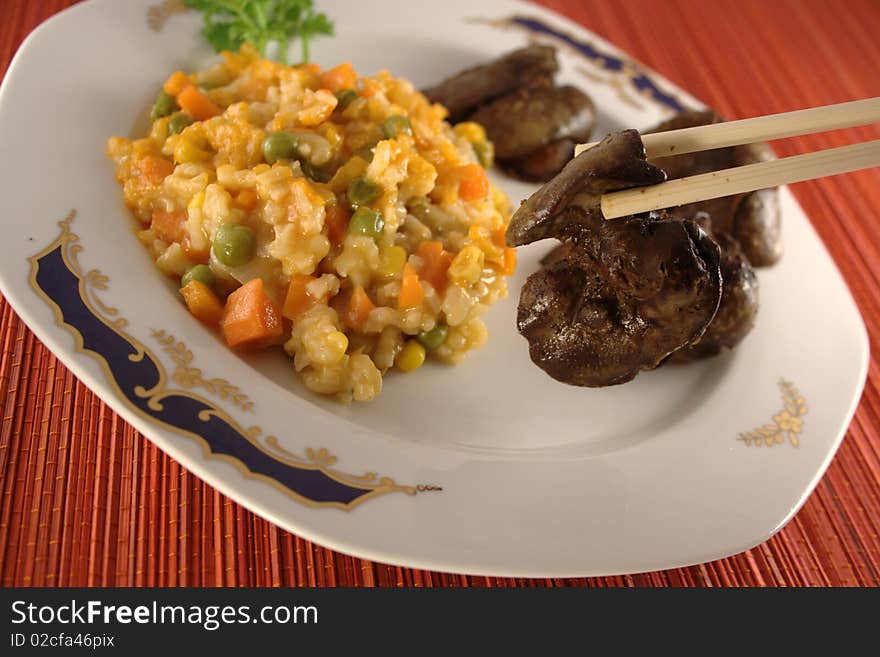 Eating chicken liver and vegetables with chopsticks.