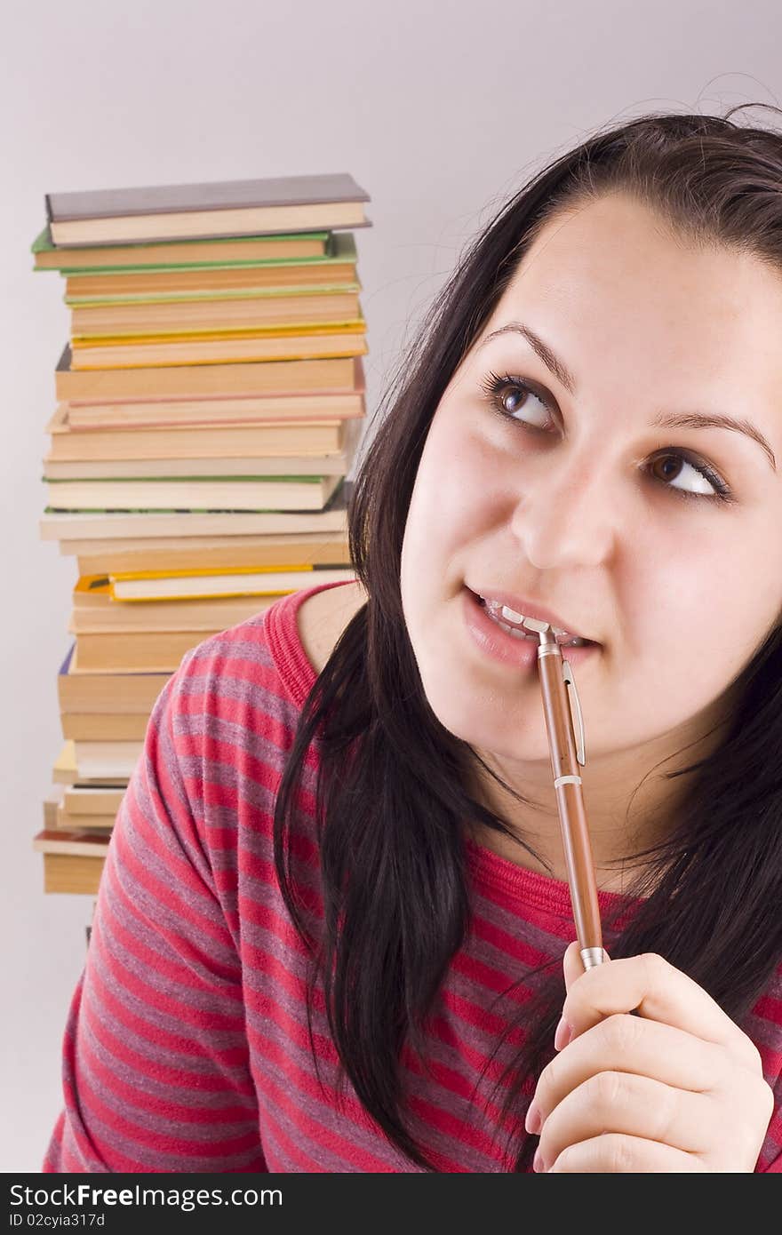 Girl thinking at homework, books in background. Girl thinking at homework, books in background