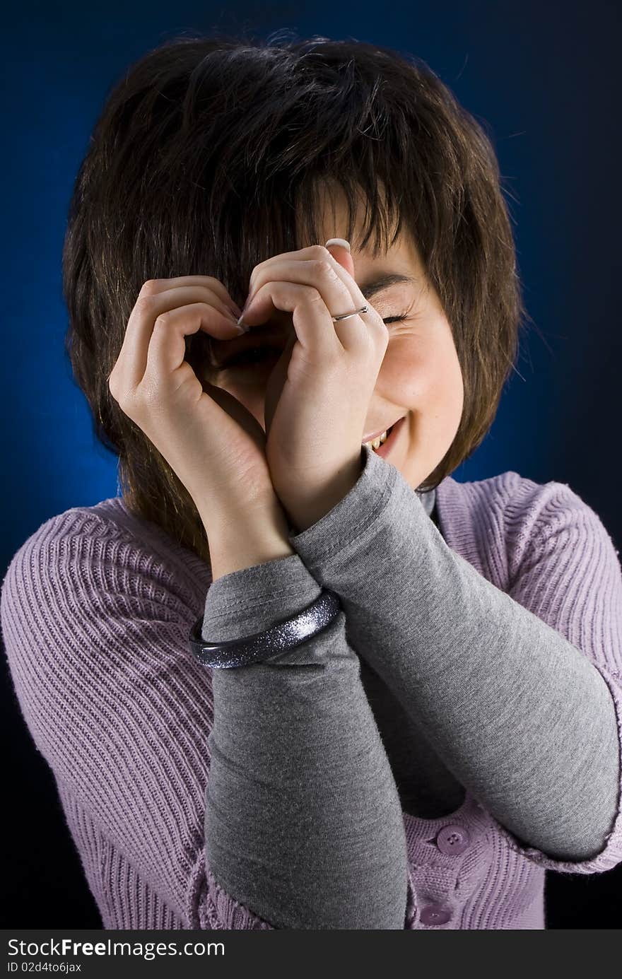 Young beautiful smiling girl giving a heart