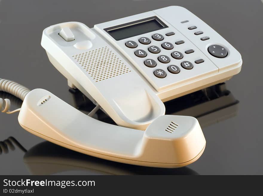 White phone of the big boss on glass desktop is shined by red light of a sunset. Mass production. Selective focus. White phone of the big boss on glass desktop is shined by red light of a sunset. Mass production. Selective focus.