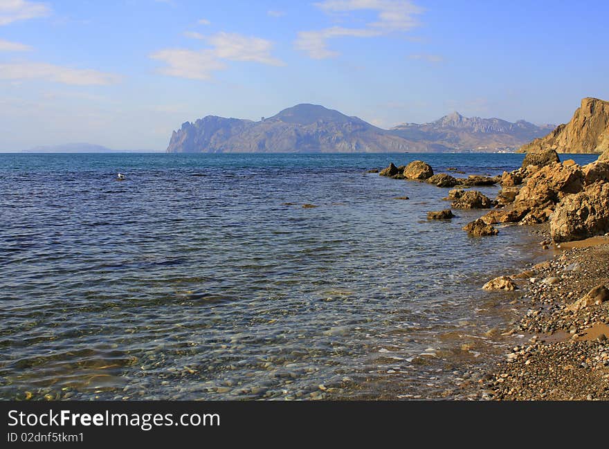 Seascape - stone, sand, clear water, and in the distance an old volcano. Seascape - stone, sand, clear water, and in the distance an old volcano