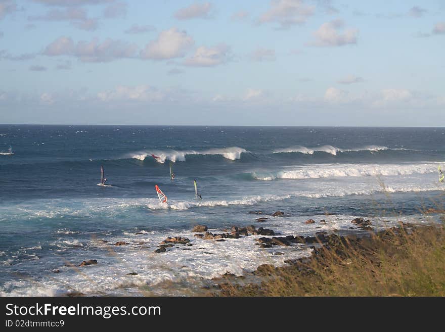 Wind surfers ride waves off the rugged east coast of the tropical island of Maui Hawaii. Wind surfers ride waves off the rugged east coast of the tropical island of Maui Hawaii.