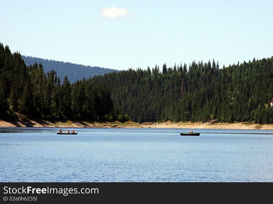 This is a picture of a beautiful lake from Romania, with people sailing in their small boats. This is a picture of a beautiful lake from Romania, with people sailing in their small boats.