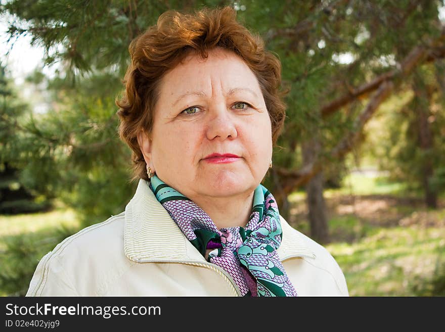 The elderly fair-haired woman in a raincoat walks