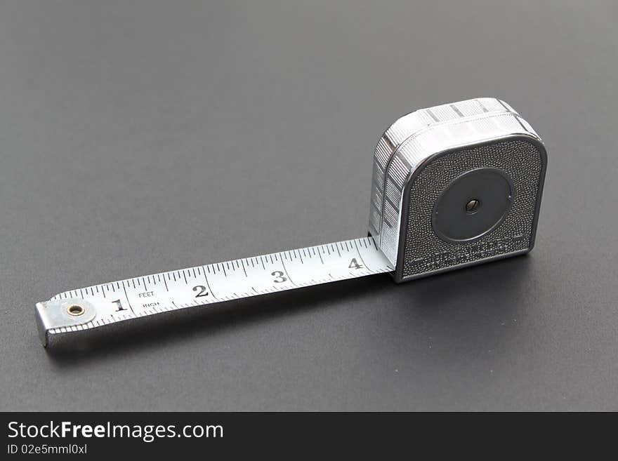 Silver tape measure on grey background