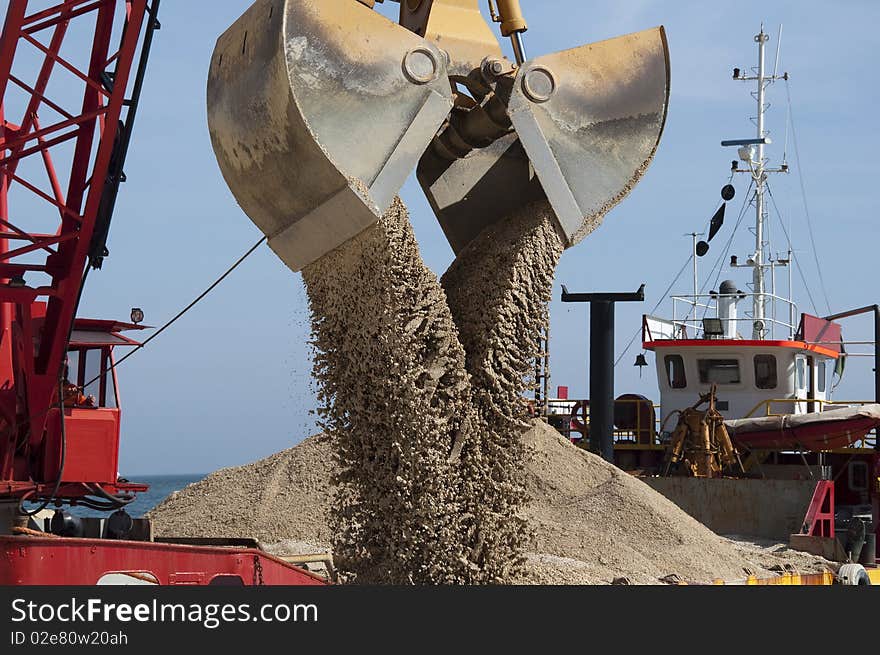 Bucket is downloading sand over the beach. Bucket is downloading sand over the beach