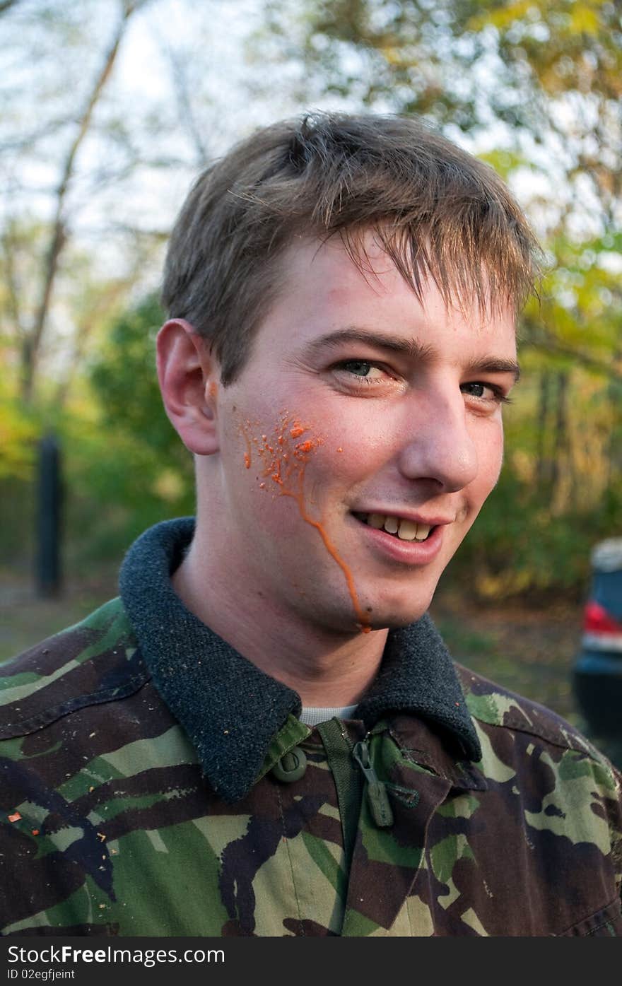 Paintball player with orange paint on the face