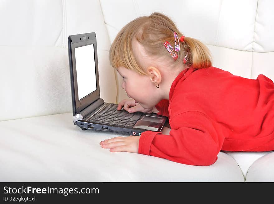 Child is laying with notebook with white screen on a sofa. Child is laying with notebook with white screen on a sofa