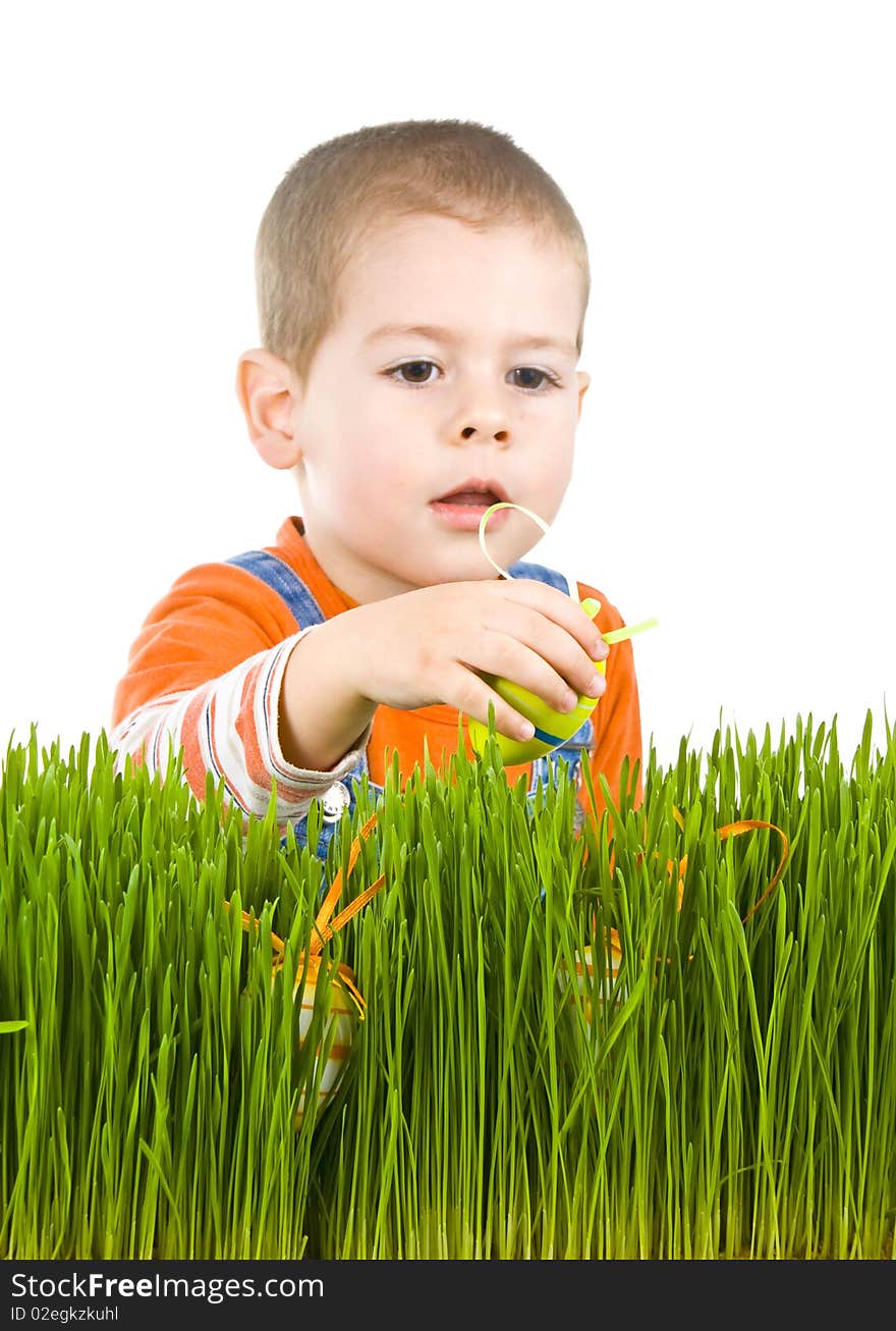 Easter egg hunt, boy searching for easter eggs hidden in fresh green grass