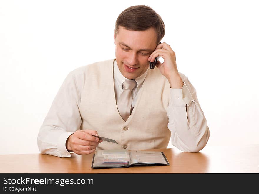 Handsome young businessman talking on the phone at the table on a white background