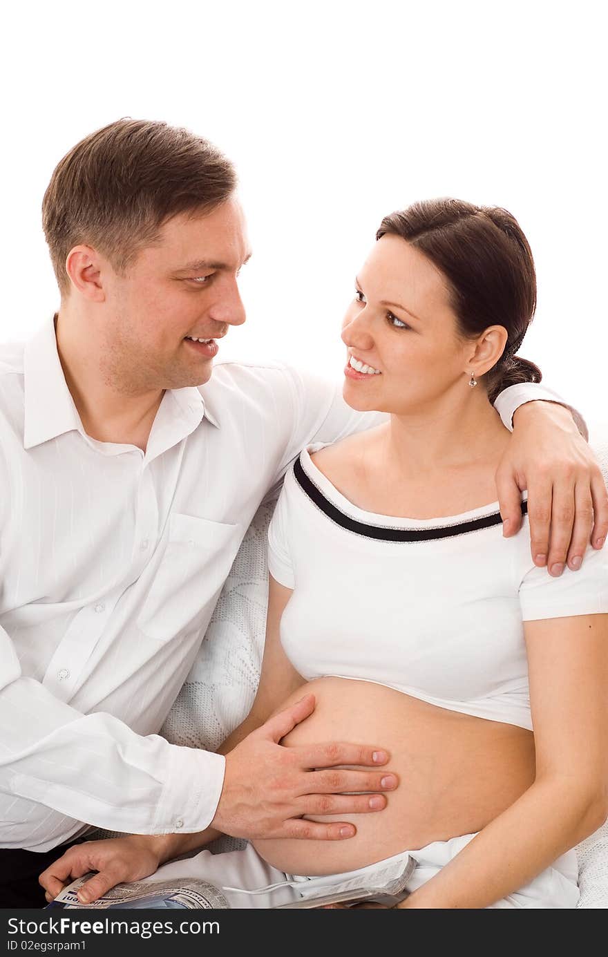 Man with his pregnant wife were sitting on a white background. Man with his pregnant wife were sitting on a white background