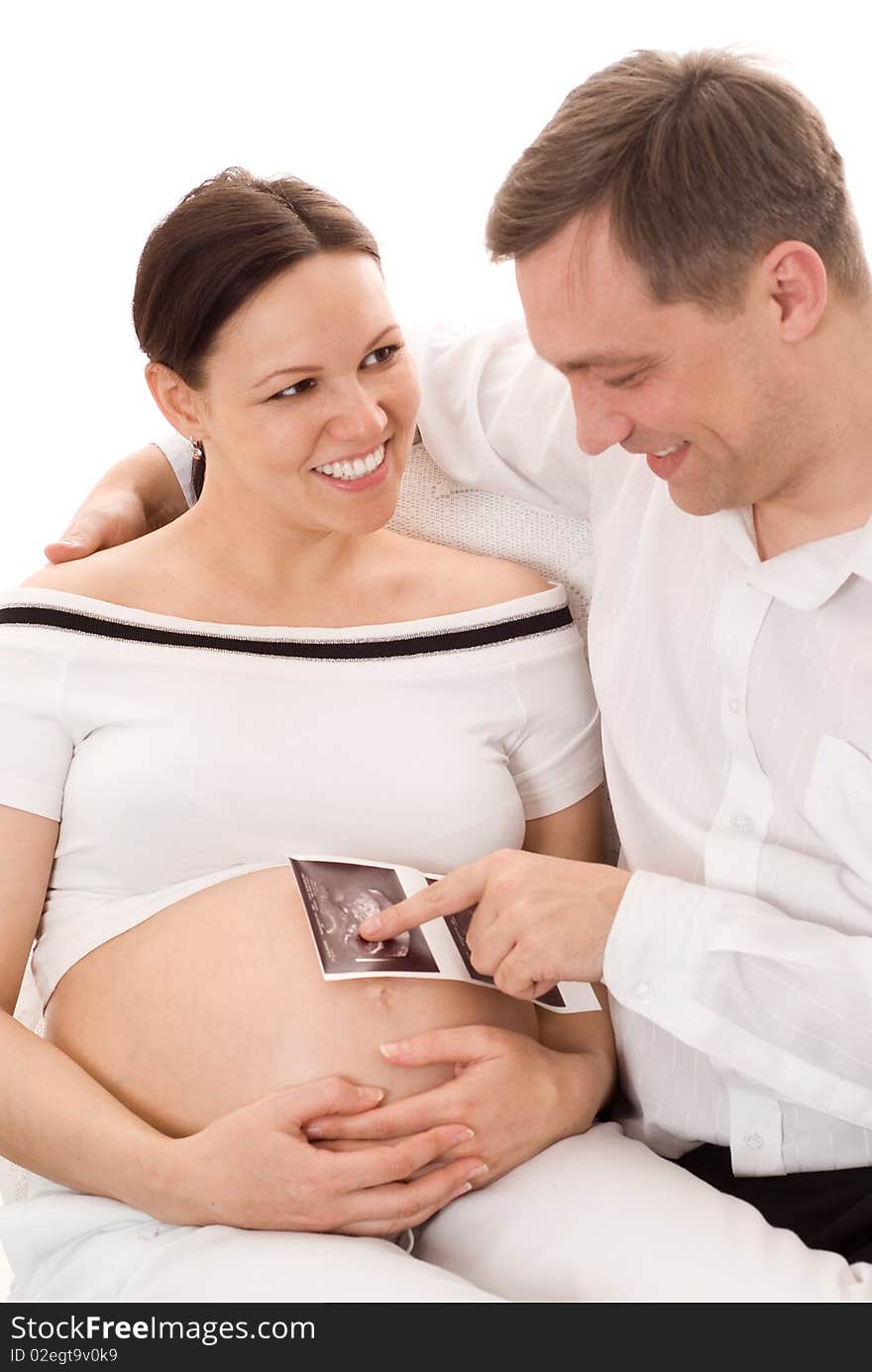 Young man with his pregnant wife sitting on a white