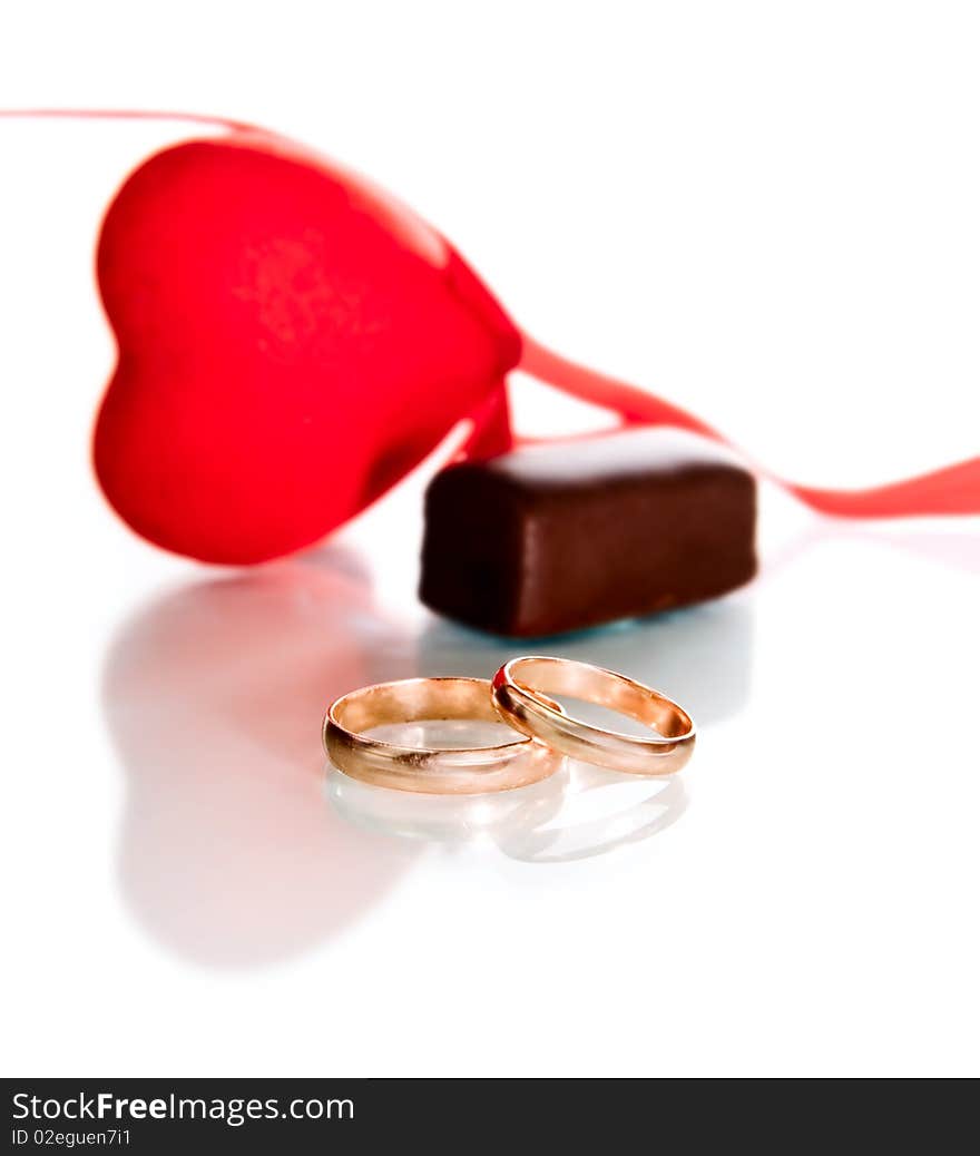 Gold rings, heart and chocolate candy isolated on white