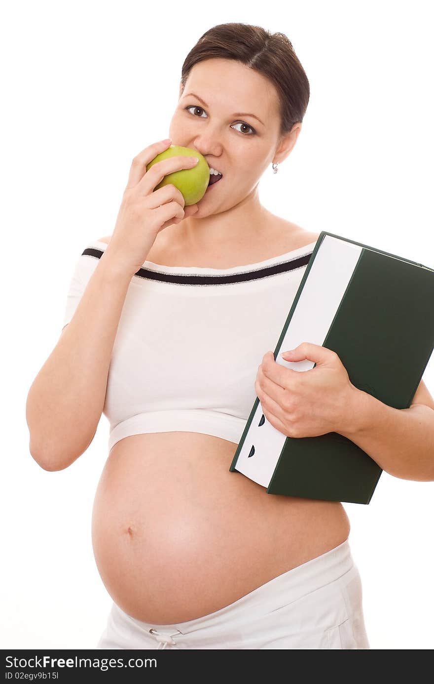 Beautiful pregnant woman holding a green book and an apple on a white