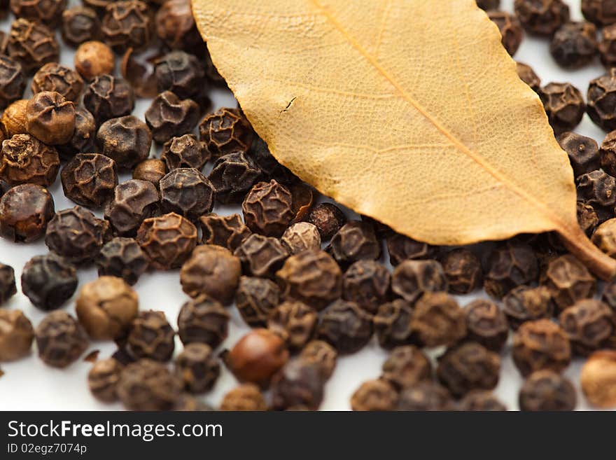 Pattern of black peppercorns and dry bay leaf  isolated on white background. Pattern of black peppercorns and dry bay leaf  isolated on white background