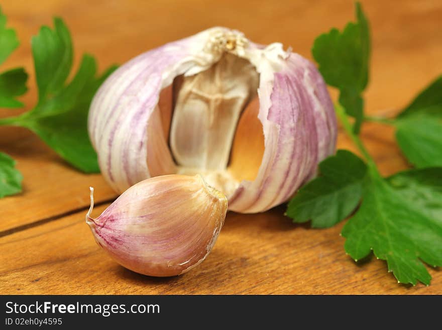 Fresh garlic clove and green parsley on wooden board. Fresh garlic clove and green parsley on wooden board