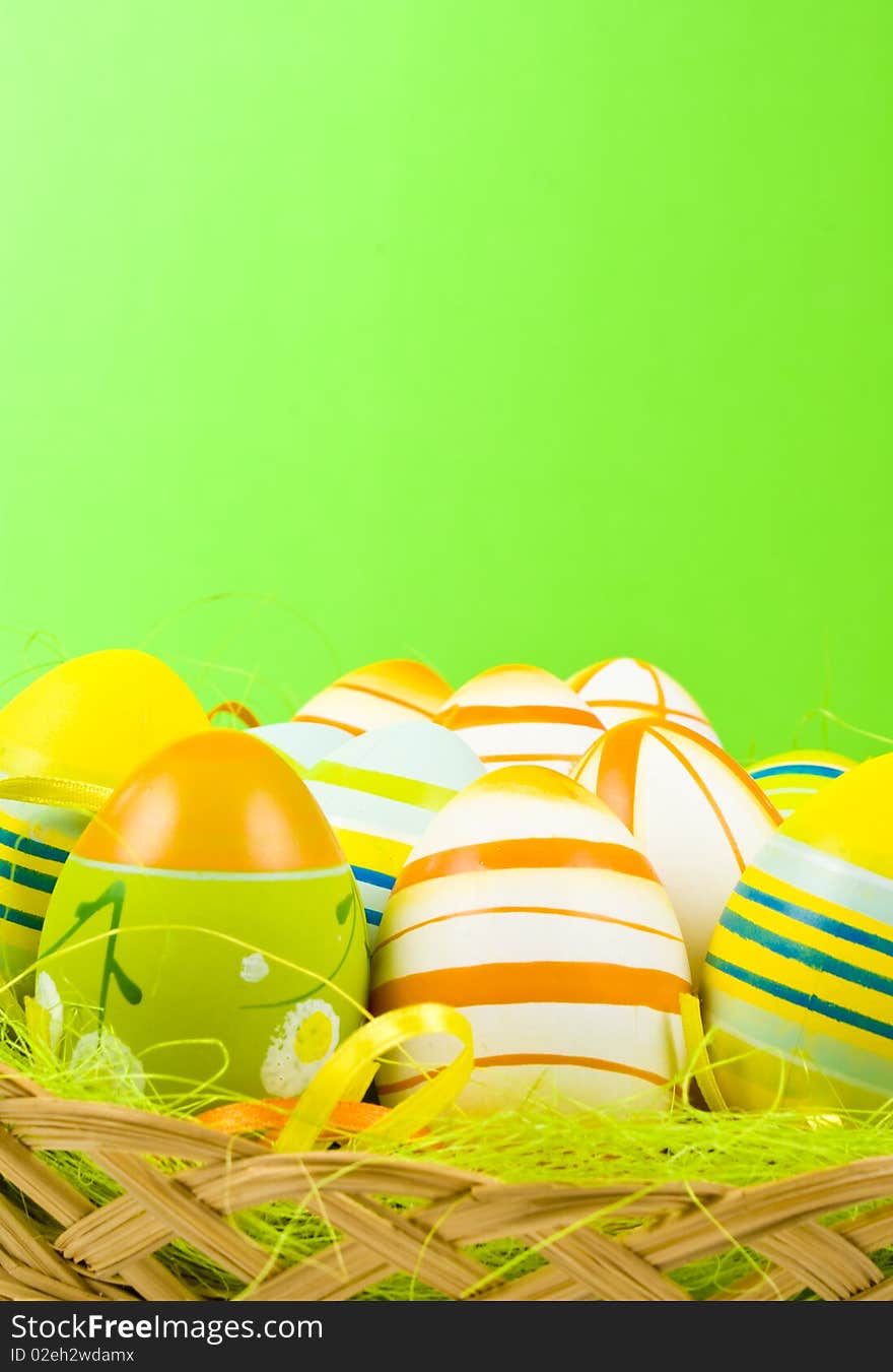 Colorful Easter Eggs basket set on green background