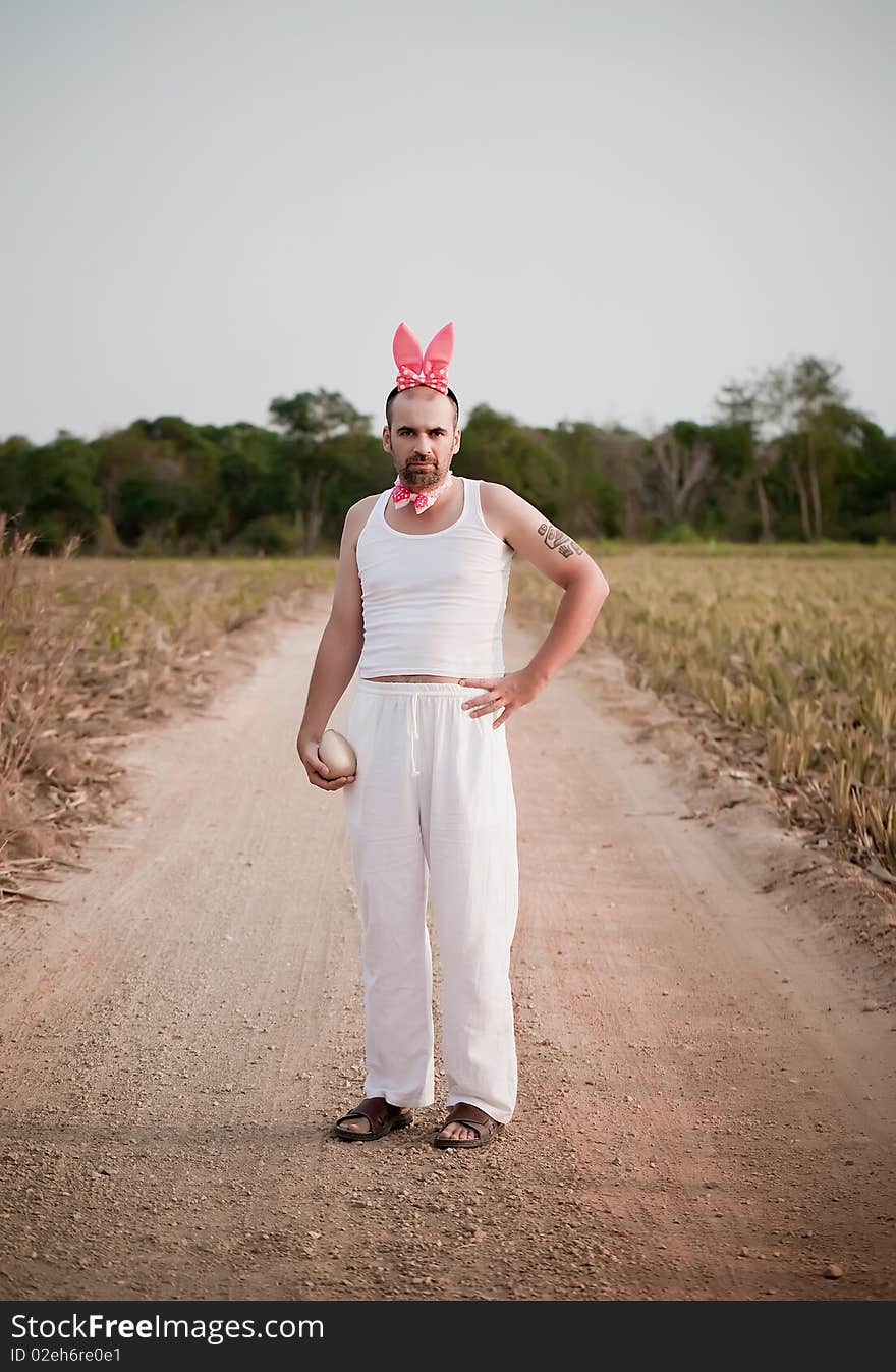 Man Wearing Bunny Hat With Big Golden Egg In The Hand. Man Wearing Bunny Hat With Big Golden Egg In The Hand