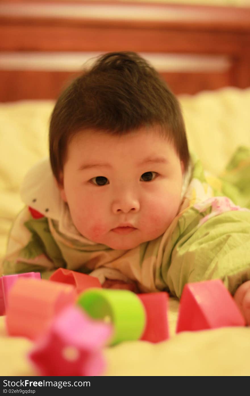 Lovely Chinese baby playing in the bed with some toys. Lovely Chinese baby playing in the bed with some toys