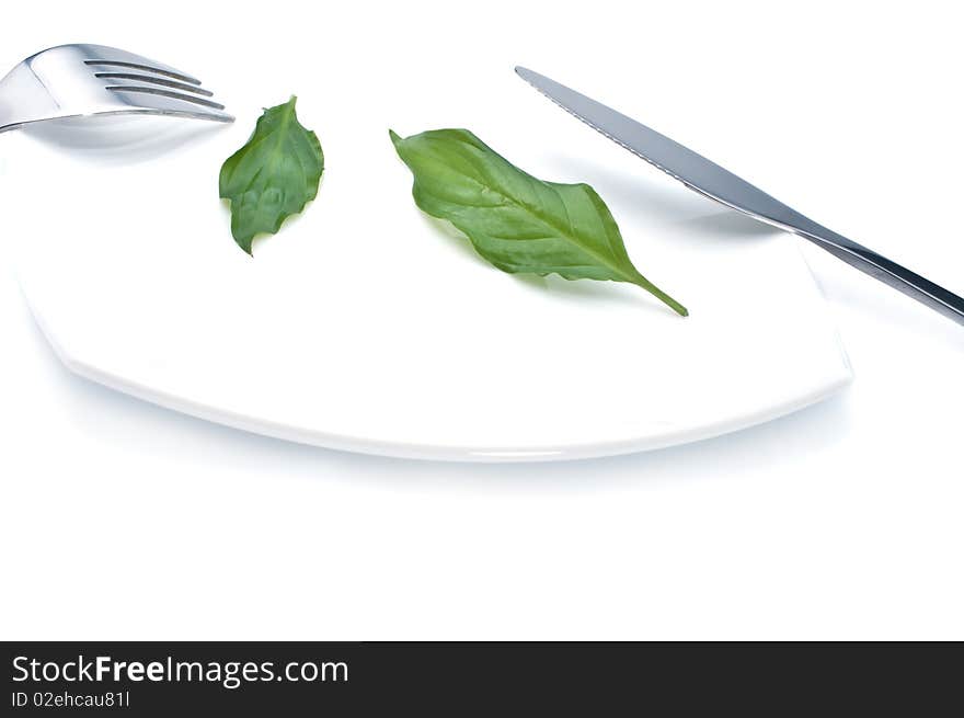 Knife , fork and fresh green leaves on a plate- diet concept. Knife , fork and fresh green leaves on a plate- diet concept