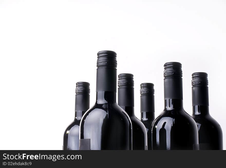 Dark wine bottles in a row against a white background.