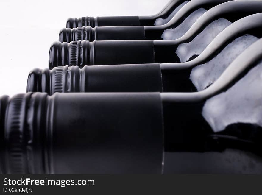 Dark wine bottles in a row against a white background. Dark wine bottles in a row against a white background.