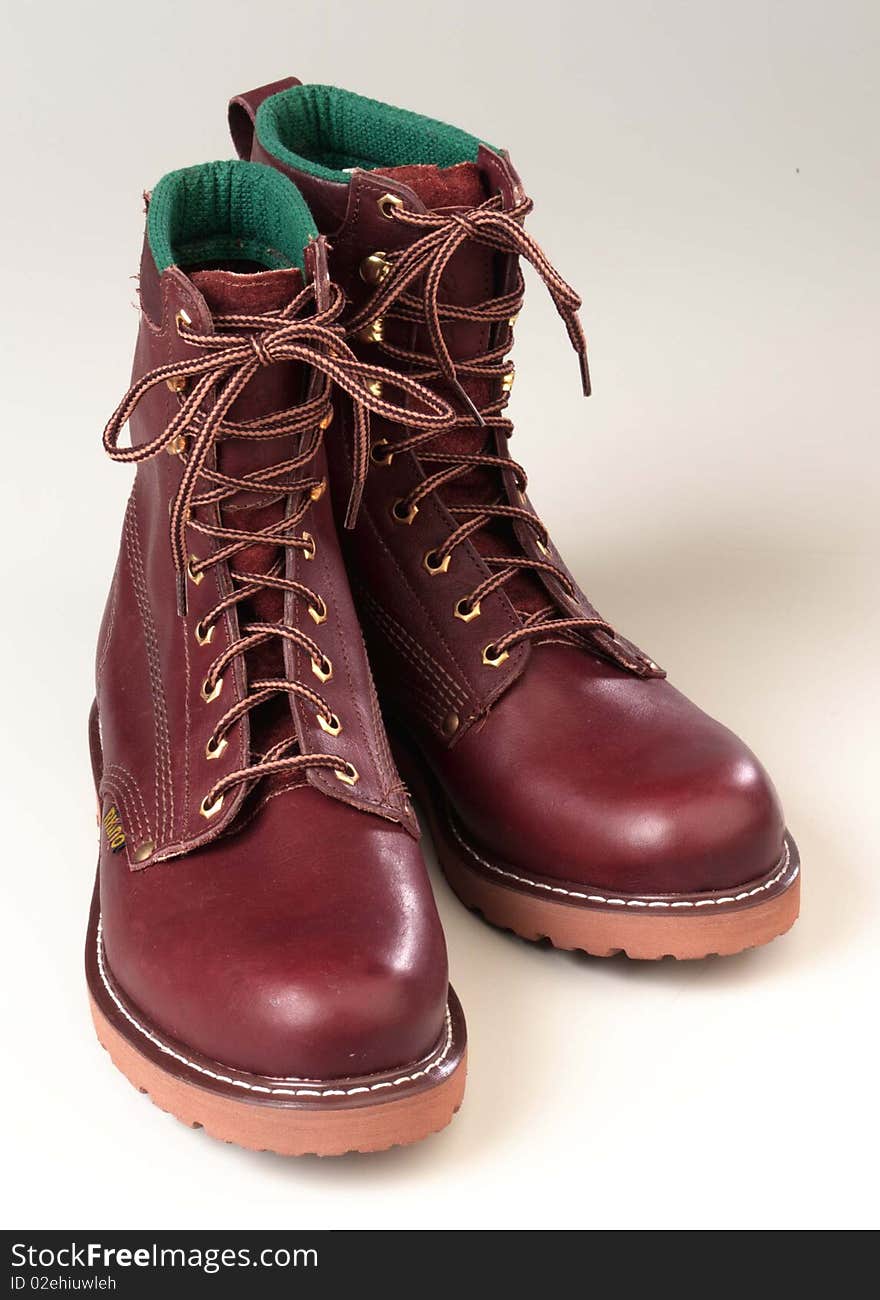 A pair of clean leather work boots all laced up and on a white background. A pair of clean leather work boots all laced up and on a white background