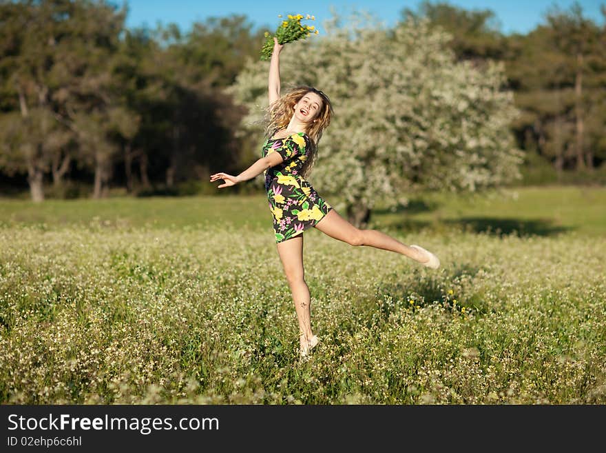 Beautiful young woman jumping in blooming meadow