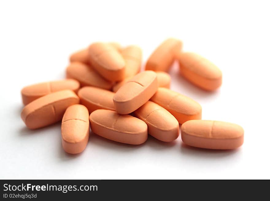 Group of light orange pills on a white background