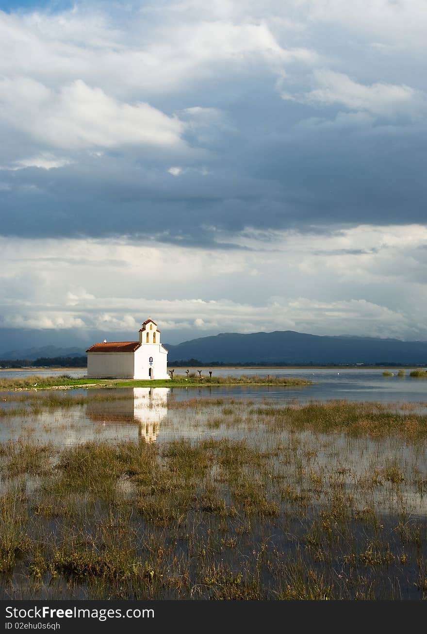 Greek church on a lake with reflection,peacefullness and a blue sky