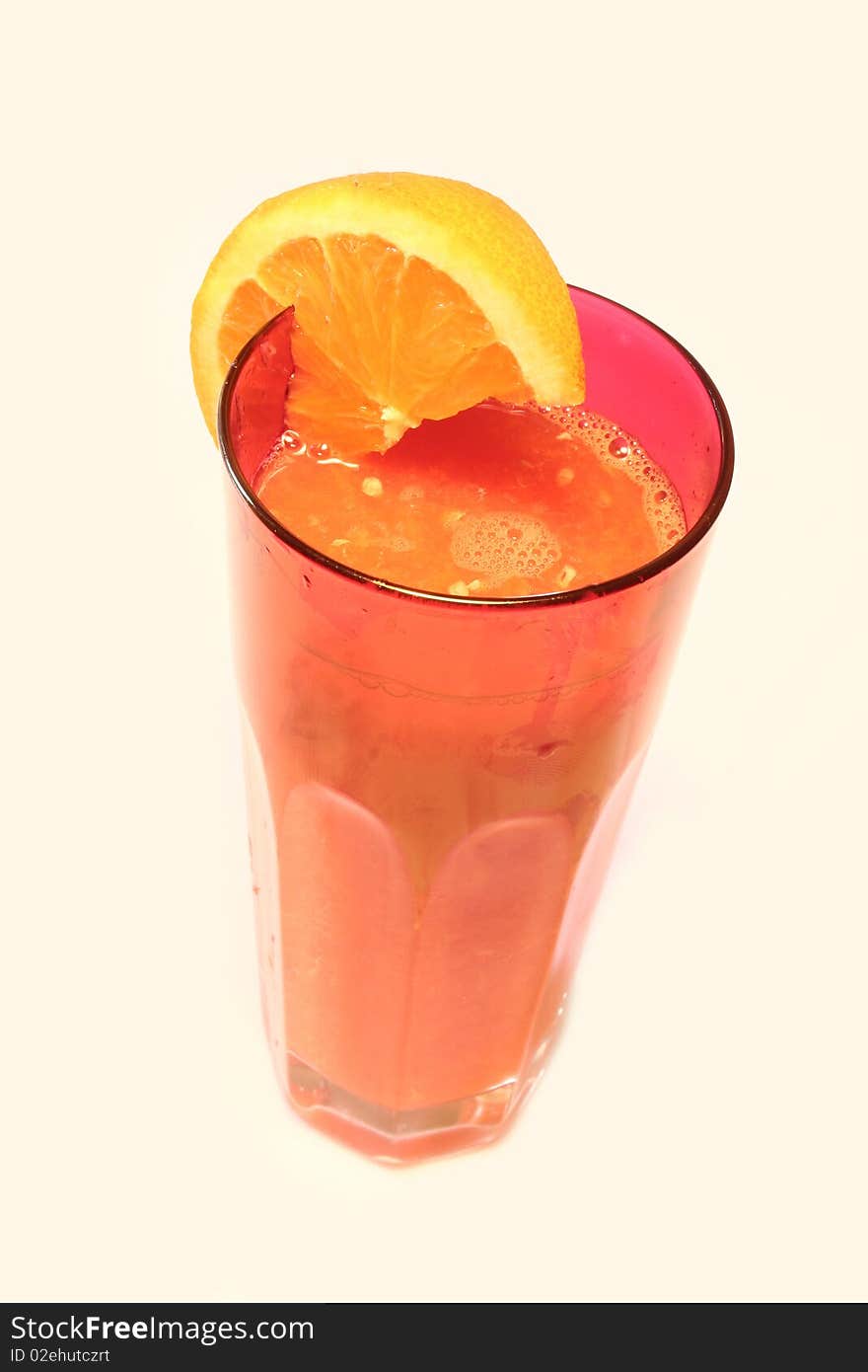 A tall glass of orange juice with orange around it