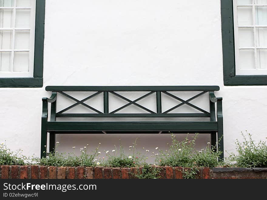 Close up of a bench in front of a old house.