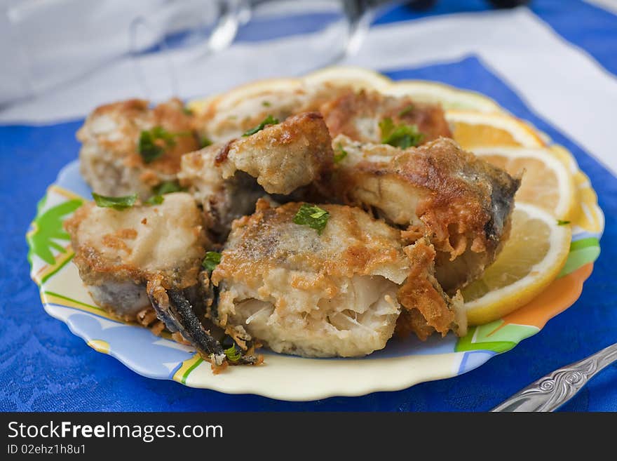 Full plate of the fried pieces of a fish of a pollack on a dark blue napkin