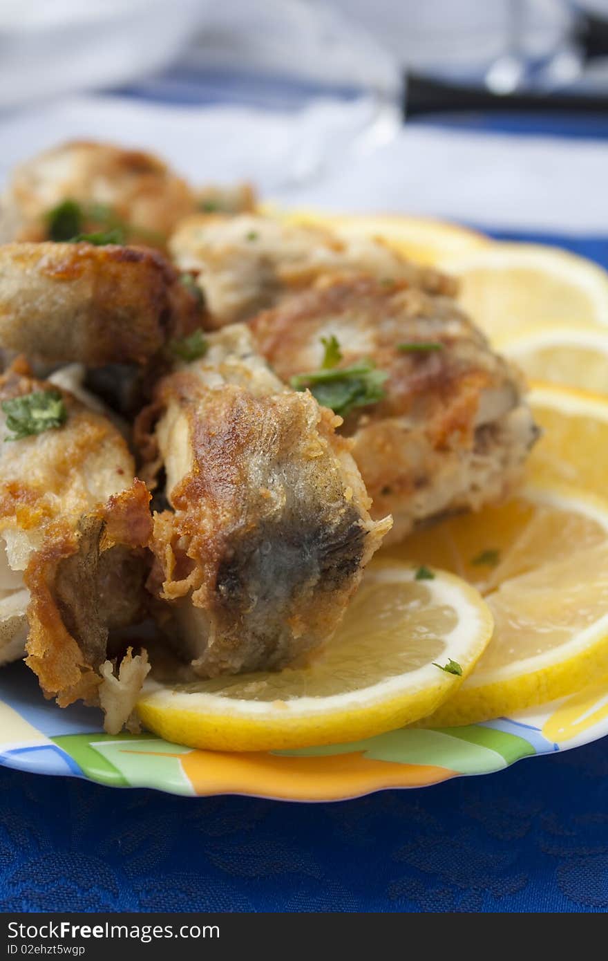 Full plate of the fried pieces of a fish of a pollack on a dark blue napkin