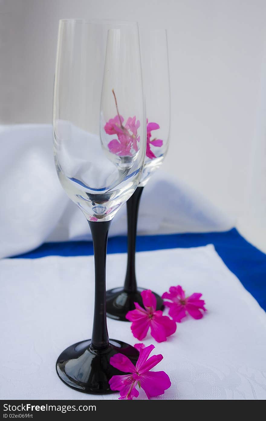 Two empty wine glasses costing on a white cloth in pink flowers