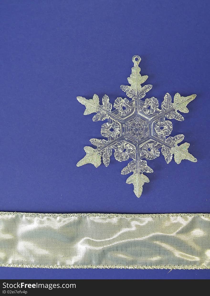 White snowflake and silver ribbon isolated on blue