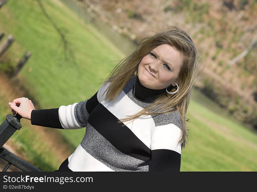 Beautiful young woman frustrated because the wind wont stop blowing her hair. Beautiful young woman frustrated because the wind wont stop blowing her hair