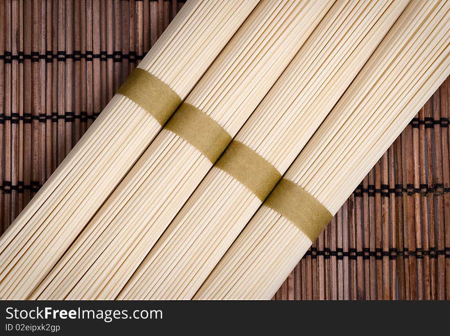 Bunches of uncooked oriental noodles on a rural mat. Bunches of uncooked oriental noodles on a rural mat.