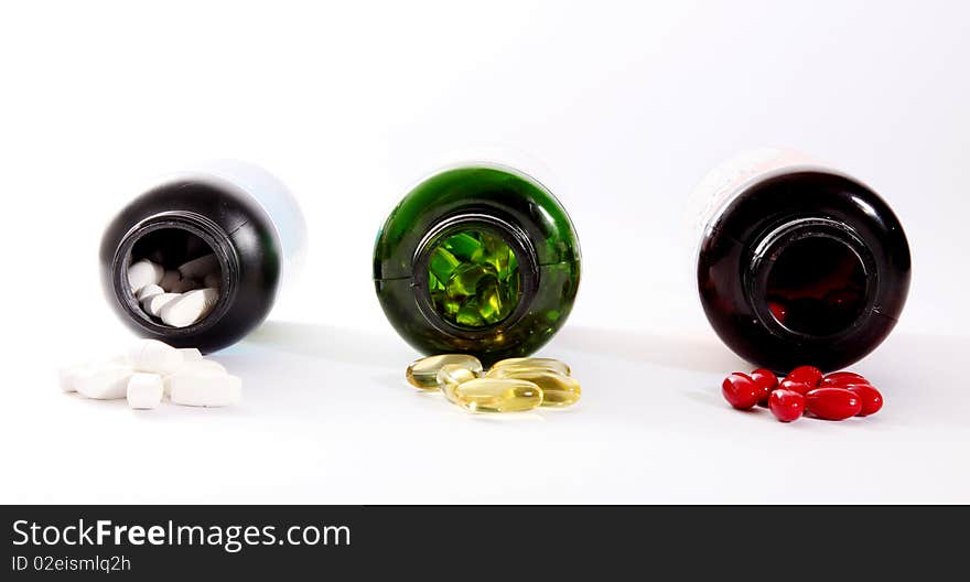 Yellow, red, white, pills and green bottles on light background. Yellow, red, white, pills and green bottles on light background