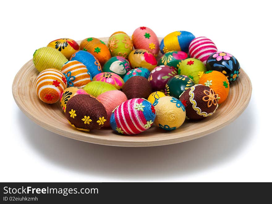 Handmade easter eggs on wooden plate. Small eggs are covered by cotton string in different colours. Additional decorative elements are glued to egg. Isolated object. Handmade easter eggs on wooden plate. Small eggs are covered by cotton string in different colours. Additional decorative elements are glued to egg. Isolated object.