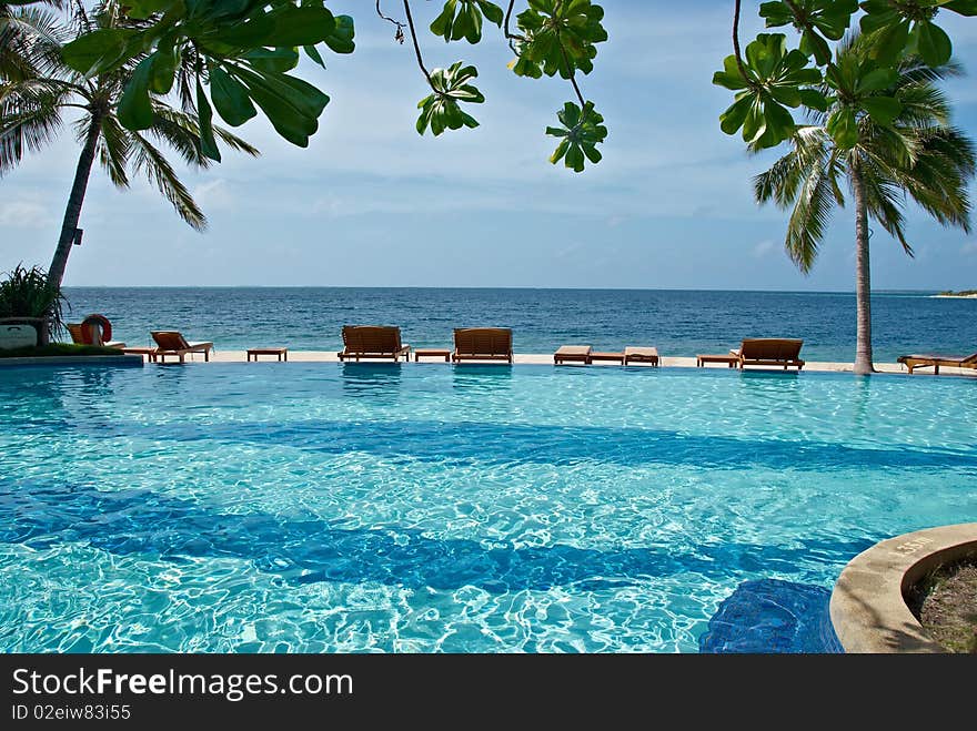 Plank bed with a chair on white sand against azure ocean. Plank bed with a chair on white sand against azure ocean